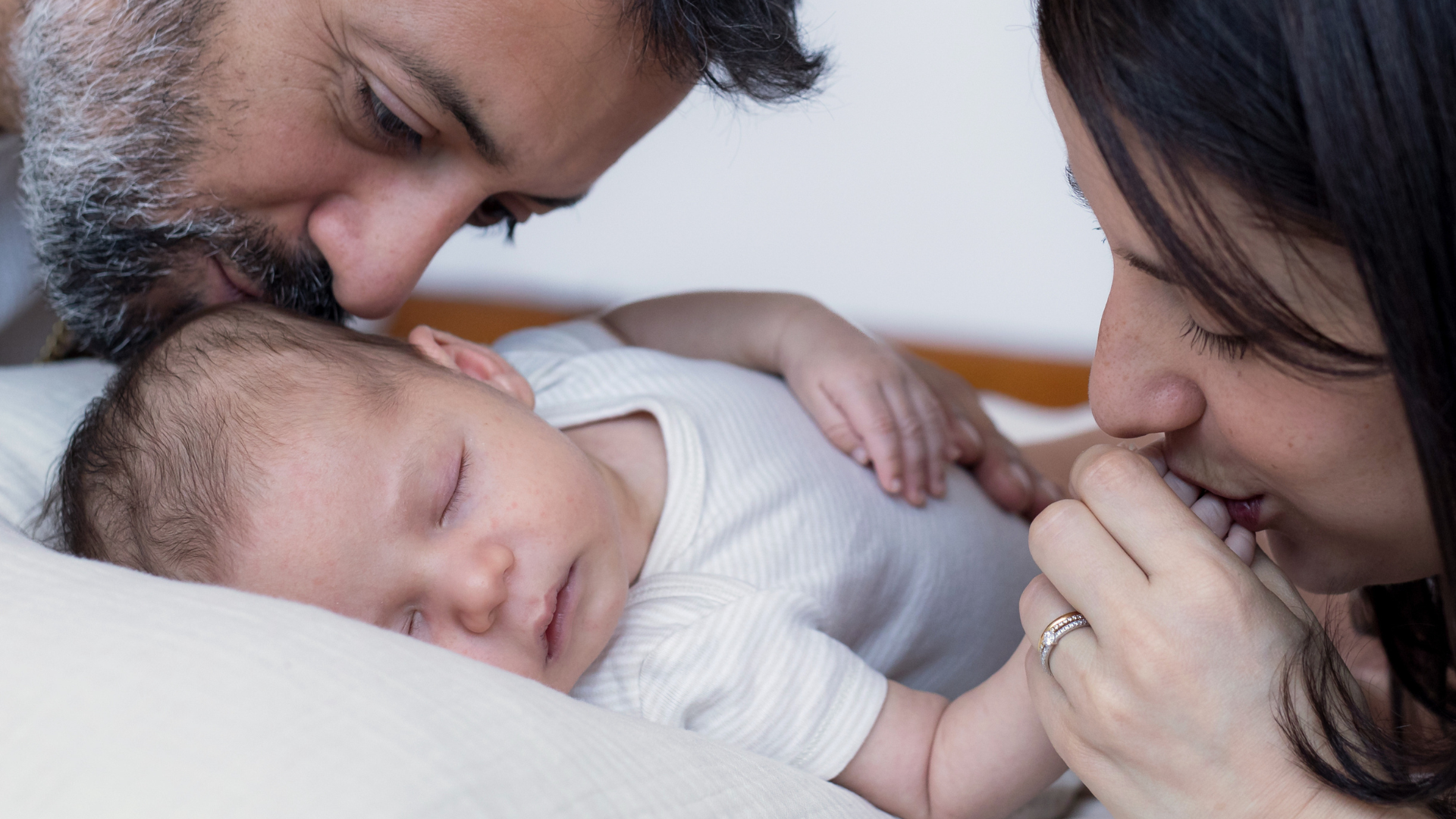Bebé recién nacido dormido junto a sus padres durante una sesión de fotografía familiar en estudio en Madrid.